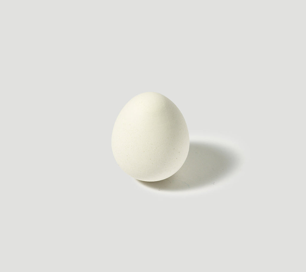 A white porcelain aroma stone with an egg shape placed on a white surface.